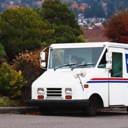 United States Postal Service USPS mail collection and delivery van in a neighborhood with a mailman. The USPS is responsible for providing postal service.