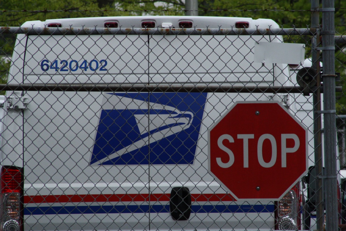 United States Postal Service (USPS) mail delivery truck in front of stop sign