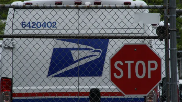 United States Postal Service (USPS) mail delivery truck in front of stop sign