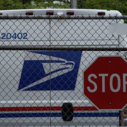 United States Postal Service (USPS) mail delivery truck in front of stop sign