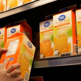 Motion of woman buying great value orange juice inside Walmart store