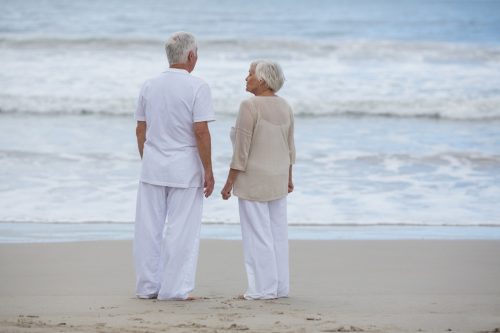 rear view of senior couple interacting with each other on the beach