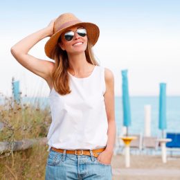 woman in a hat and sunglasses looking happy on a deck