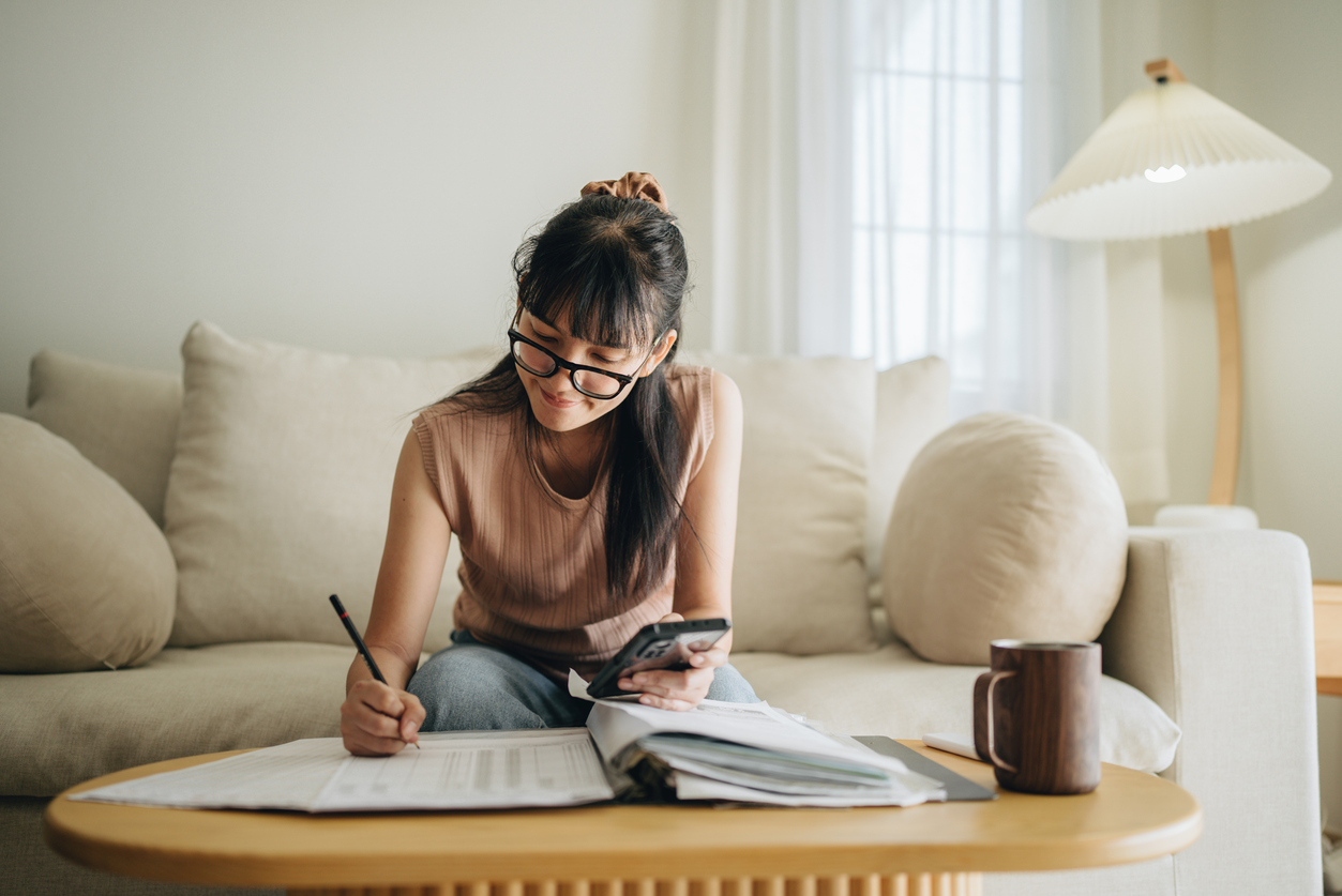 A woman sitting on her couch while preparing her finances or tax filing