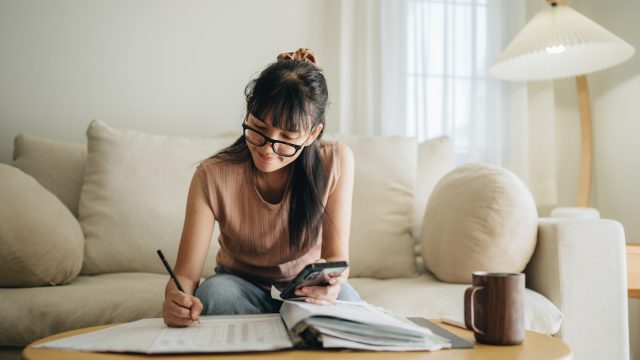 A woman sitting on her couch while preparing her finances or tax filing