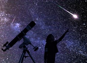 Silhouette of young girl with telescope watching meteor shower