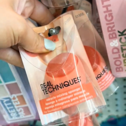 Woman's hand holding a makeup sponge in Dollar Tree