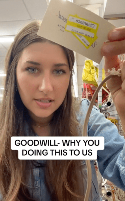 Still from Taylor Beagle's TikTok of her holding up a target price tag on a goodwill item; the caption reads "Goodwill - why you doing this to us?"
