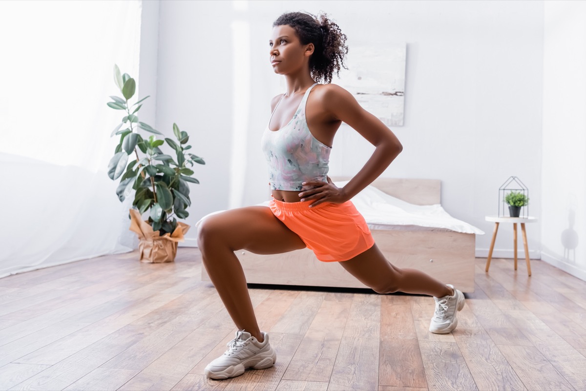 Woman doing lunges while training in bedroom