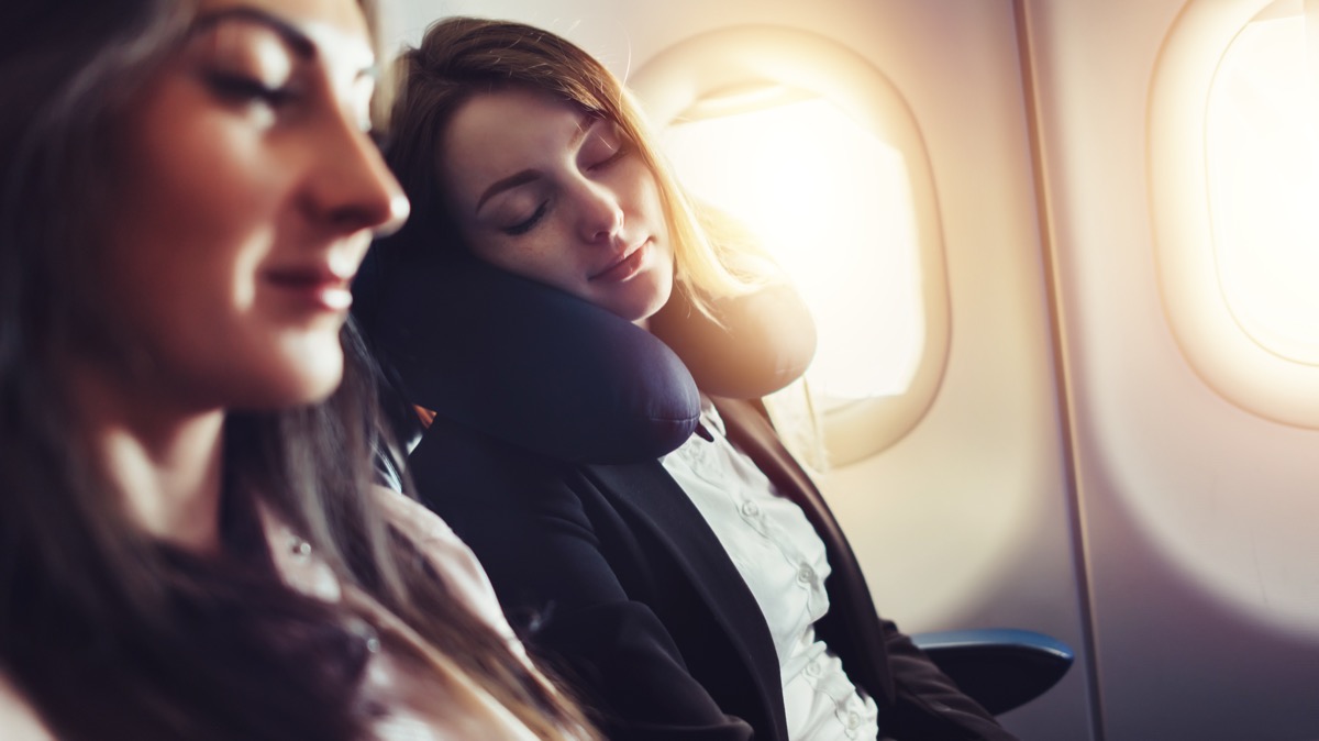 A female passenger sleeping on neck cushion in airplane