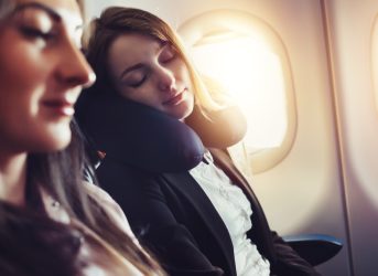 A female passenger sleeping on neck cushion in airplane