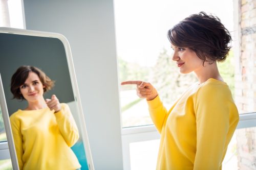 Young woman pointing at herself in the mirror
