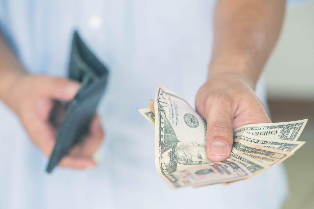 A man holds dollars in his hands. paying in cash, people, business, finances and money concept.