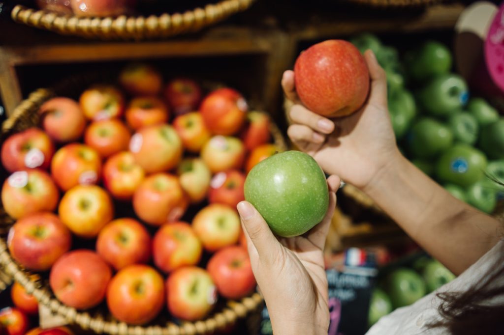 Close up on woman's hands holding green and red apple
