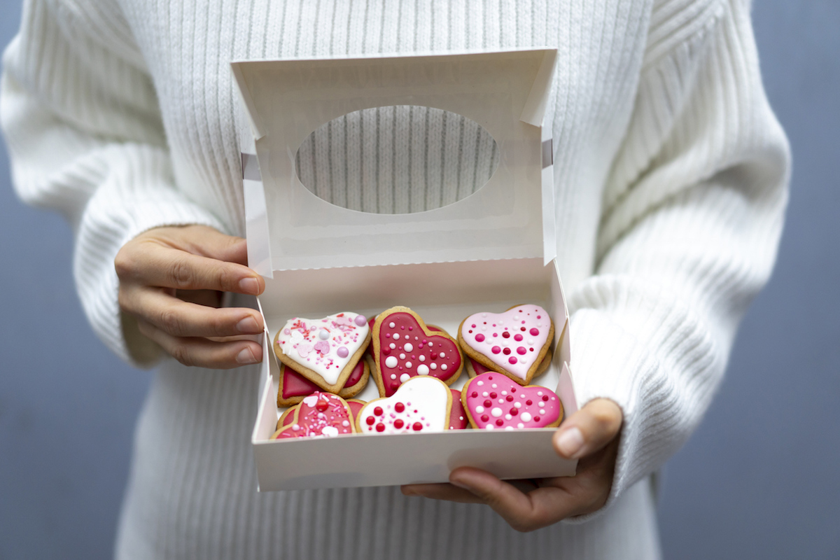 Woman holding box with Valentine's cookies