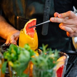 Close-up of bartender putting grapefruit in a fresh cocktail in the bar