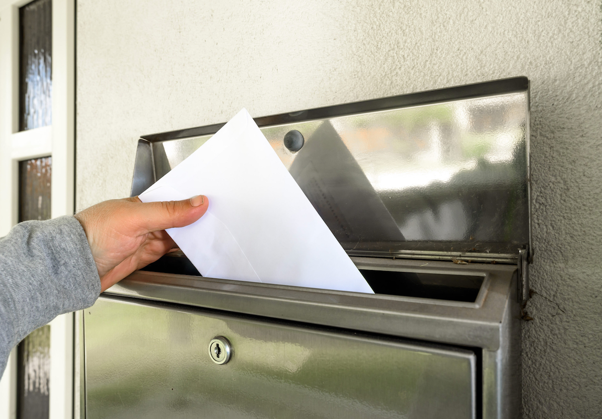 hand putting mail in mailbox