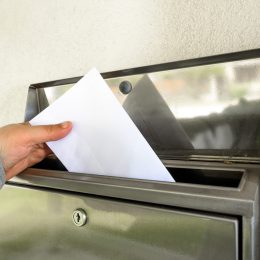 hand putting mail in mailbox