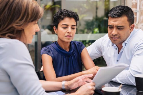 A couple speaking with a financial planner with serious looks on their faces