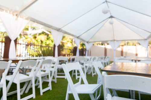 A group of chairs and tables under a white tent. Taken at a wedding before guests arrive.