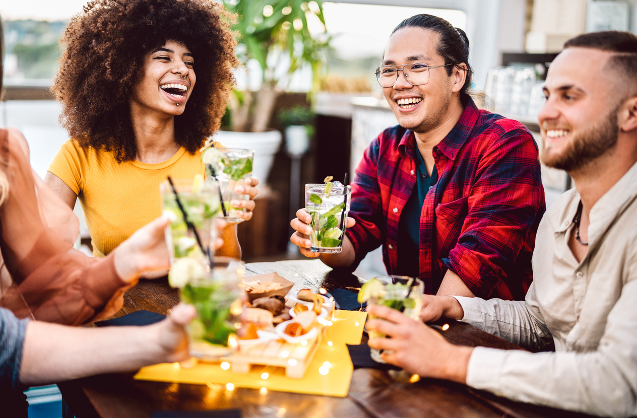 Young friends raising their cocktails to cheers at a dinner party