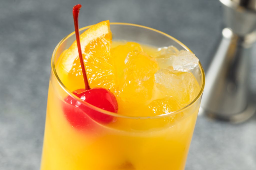 A close up of a Harvey Wallbanger cocktail with a cherry garnish