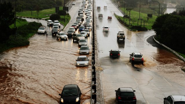A flooded highway with cars trying to pass through water