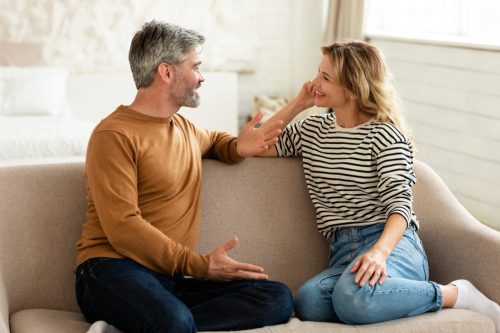 man and woman talking on a couch asking one another questions