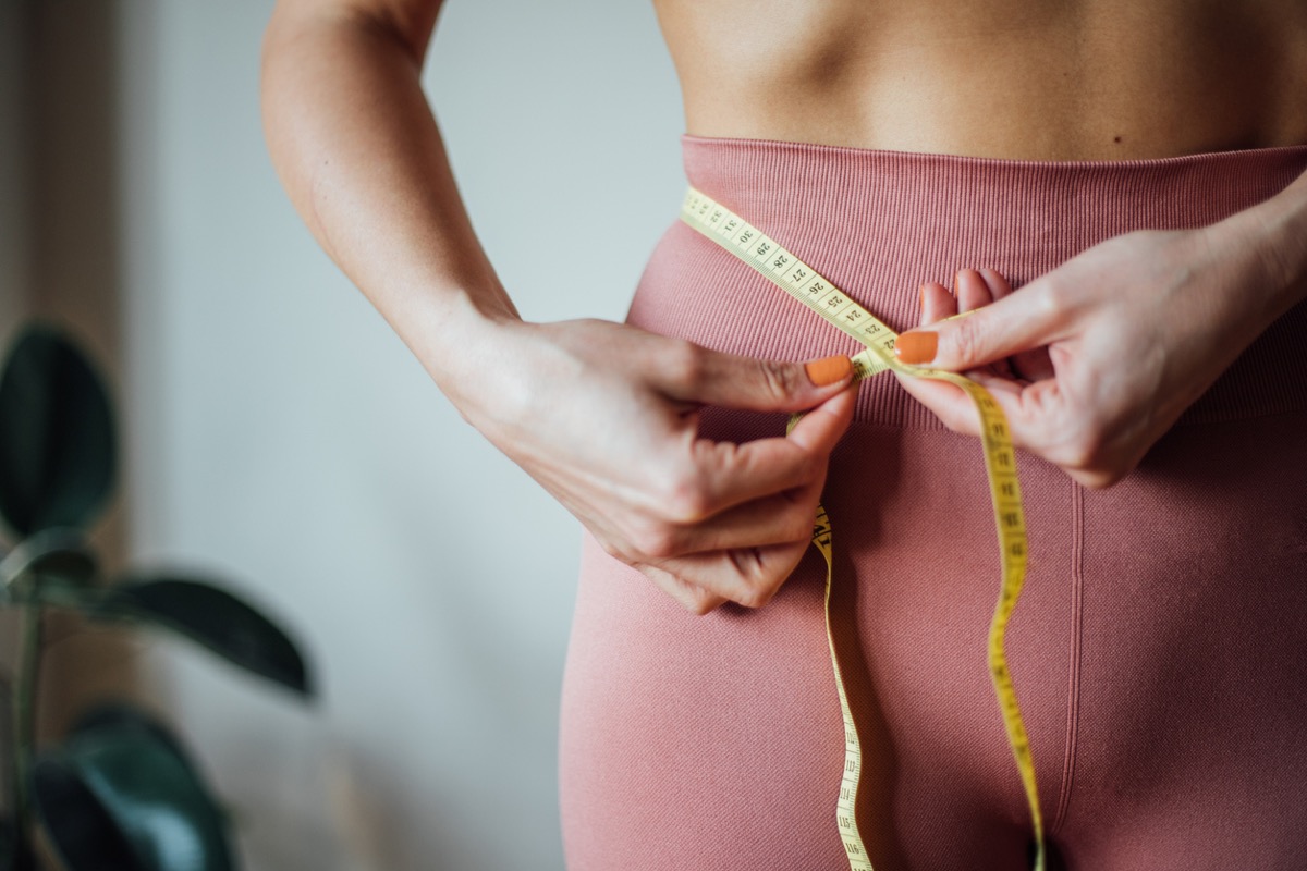 woman taking waist measurements