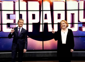 Ken Jennings and Amy Schneider posing in front of a Jeopardy board