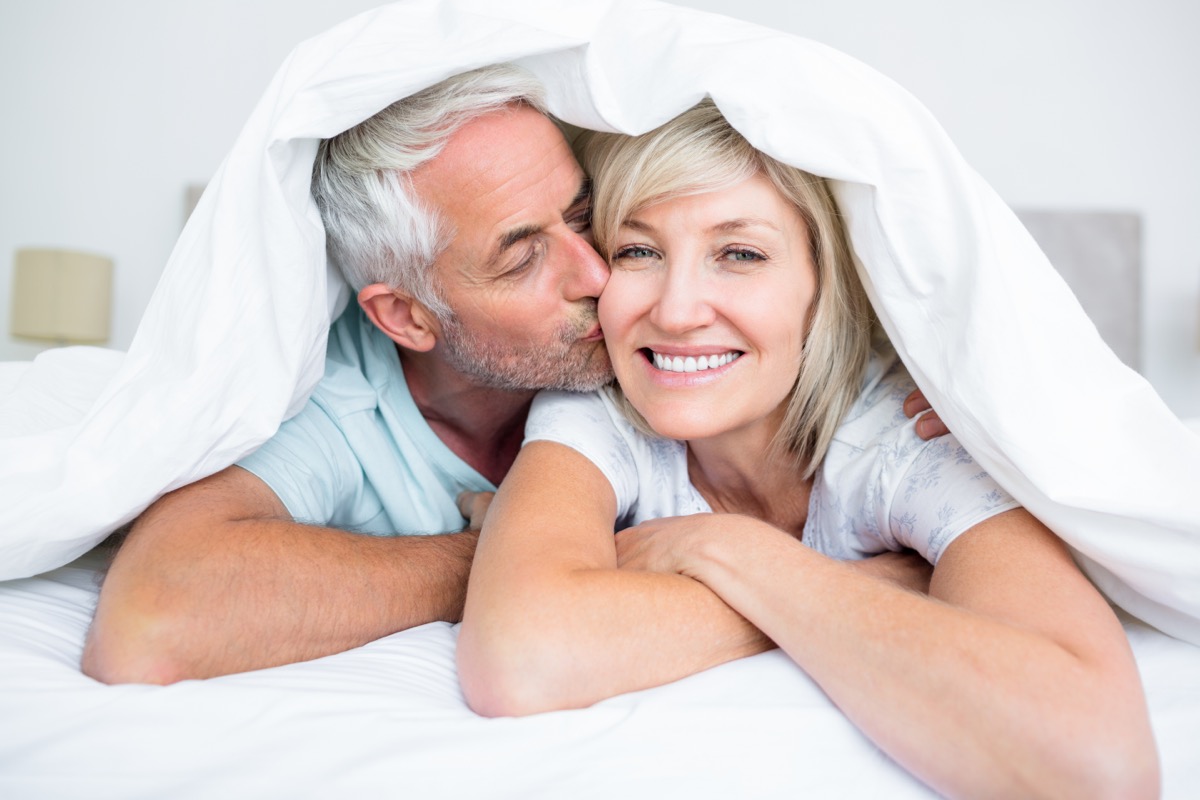 Closeup of a mature man kissing womans cheek in bed at the home