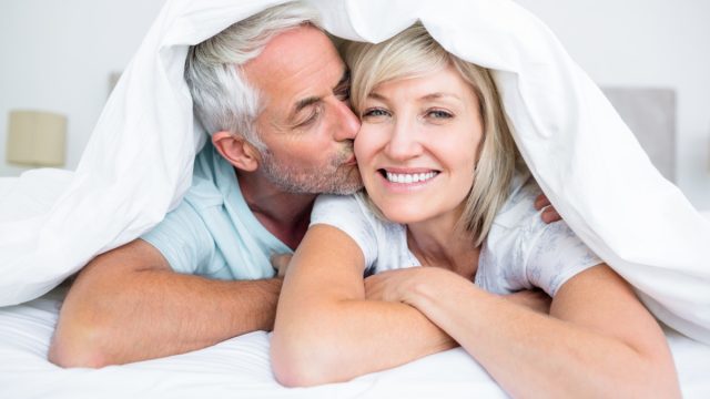 Closeup of a mature man kissing womans cheek in bed at the home