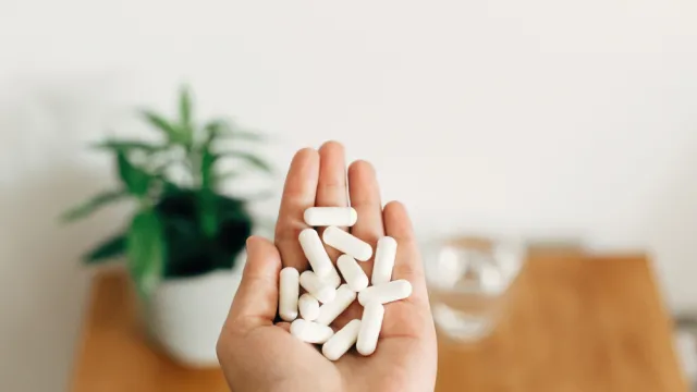 A close up of an outstretched palm holding white supplement capsules