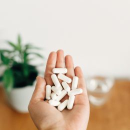 A close up of an outstretched palm holding white supplement capsules