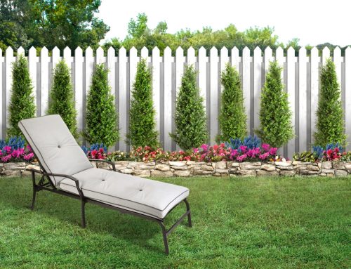 Chaise Lounge in a backyard with green grass and white wooden picket fence