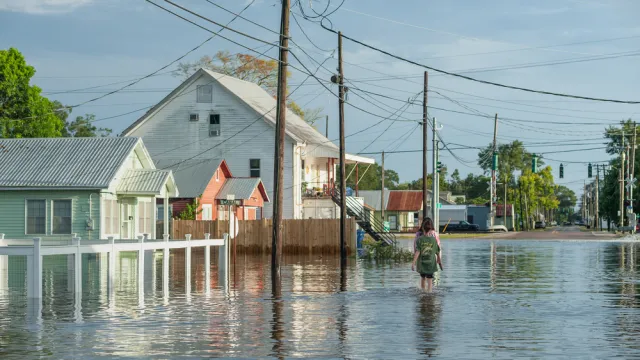 Two people walking through floodwaters next to homes