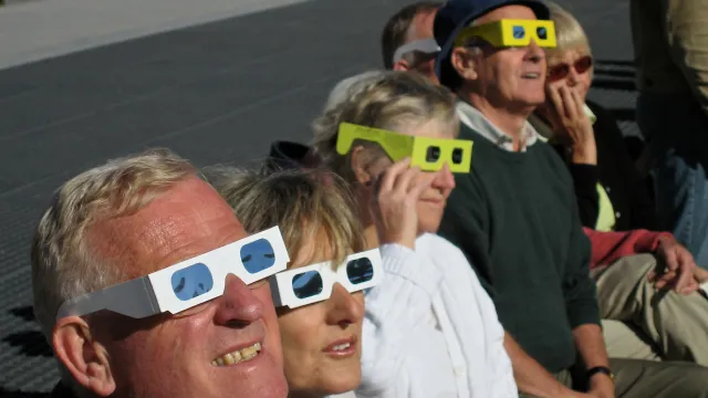A group of people watching a solar eclipse wearing safety glasses