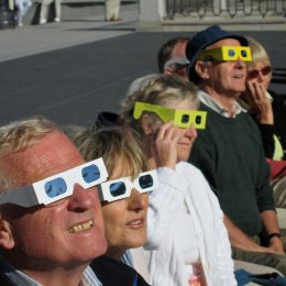 A group of people watching a solar eclipse wearing safety glasses