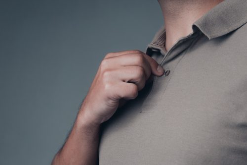 close up of a young adult male buttons up his green polo shirt