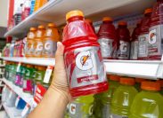 A view of a hand holding a bottle of Gatorade, on display at the grocery store.