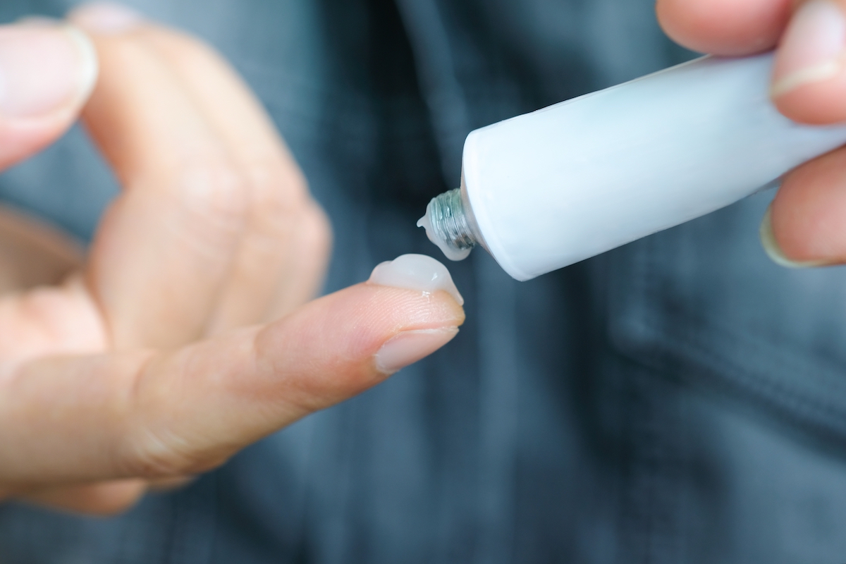 Closeup of a person putting topical gel on their finger
