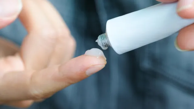 Closeup of a person putting topical gel on their finger