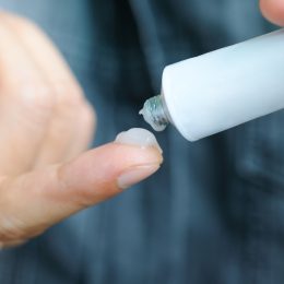 Closeup of a person putting topical gel on their finger