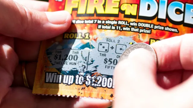 close up of person using a penny on a scratch-off ticket