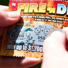 close up of person using a penny on a scratch-off ticket