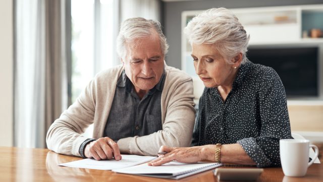 A senior couple sitting at a table looking over documents