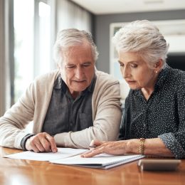 A senior couple sitting at a table looking over documents