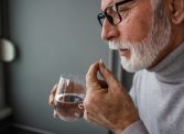 A senior man taking a supplement capsule with a glass of water