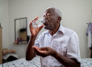 A senior man taking medicine with a glass of water