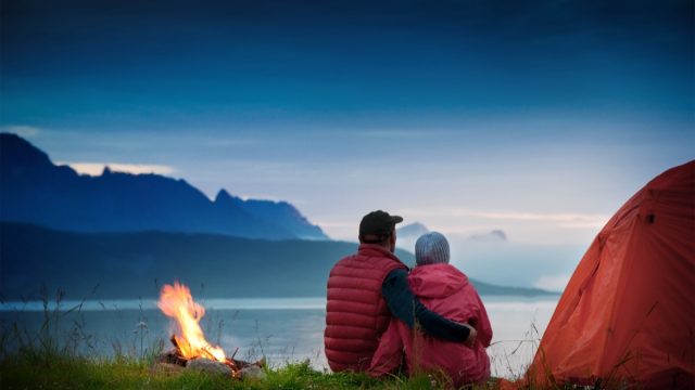 couple sitting by bonfire on camping trip